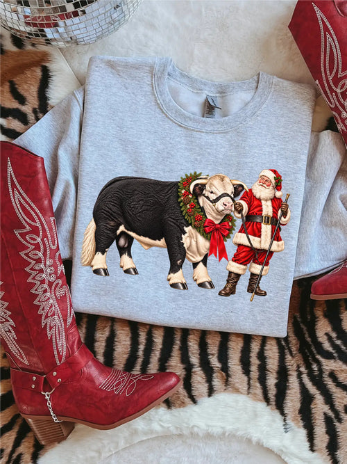 Gray shirt featuring Santa beside a black-and-white steer with festive greenery and a red bow